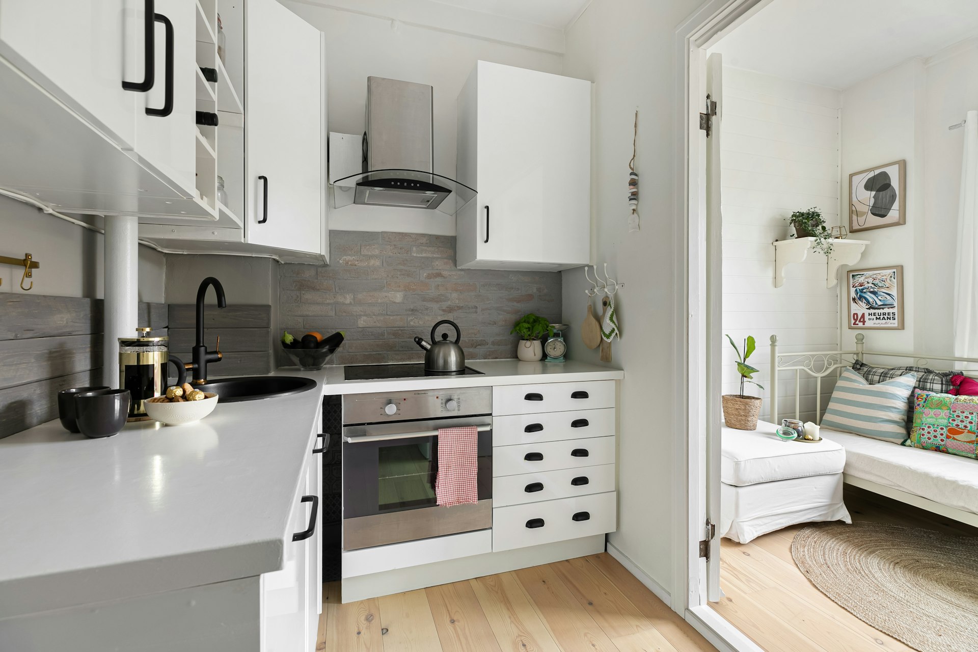 A kitchen with white cabinets and wood floors